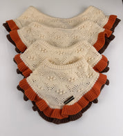 Four dog bandanas stacked diagonally on a white background. The bandanas are cream-colored with textured knit patterns and ruffled trim in orange and dark brown.
