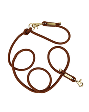 A brown rope dog leash with gold-tone metal hardware, including a snap hook clasp and a small brand tag, displayed on a clean white background.